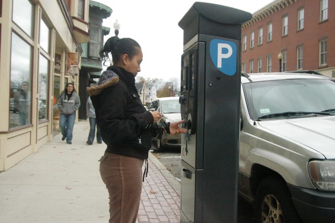 Zaidaly Gonzales, of Taunton, places a dollar in one of the new parking meter kiosks located downtown on Broadway near the district courthouse.

TDG Photo by Marc Larocque