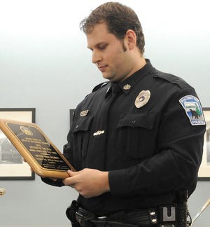Pocono Township Police Officer Aaron Anglemyer admires the plaque he received for being Officer of the Year for 2012 in Monroe County. The award was presented to him at the Pocono Township supervisors meeting Monday.