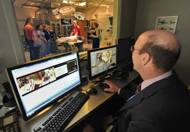 Will.Dickey@Jacksonville.com Gene Richie, operations manager, sits in the control room of the simulated surgical suite at the Mayo Clinic while a tour group comes through.