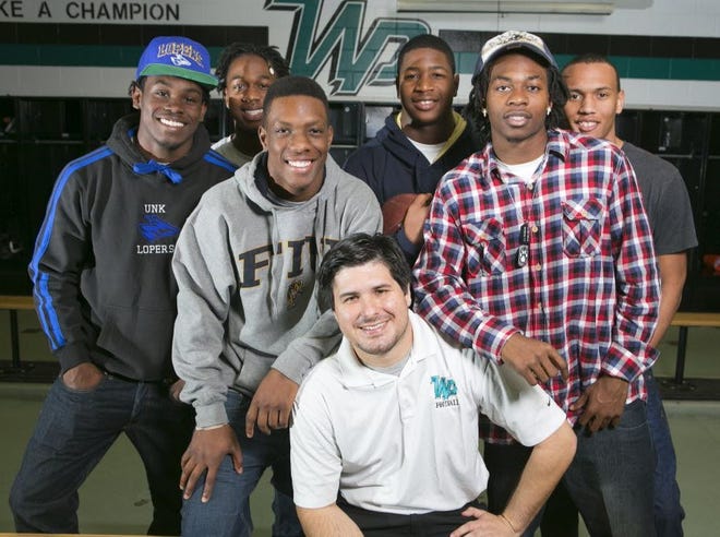 West Port football stars from left Kalen Woodyard, Jerald Whitehead, Alfonso Randolph, Jonnu Smith, Markee Hayes, and Nathan Penix are shown with head coach Ryan Hearn in the locker room at West Port High School. They are part of the best scholarship class for West Port High School football.