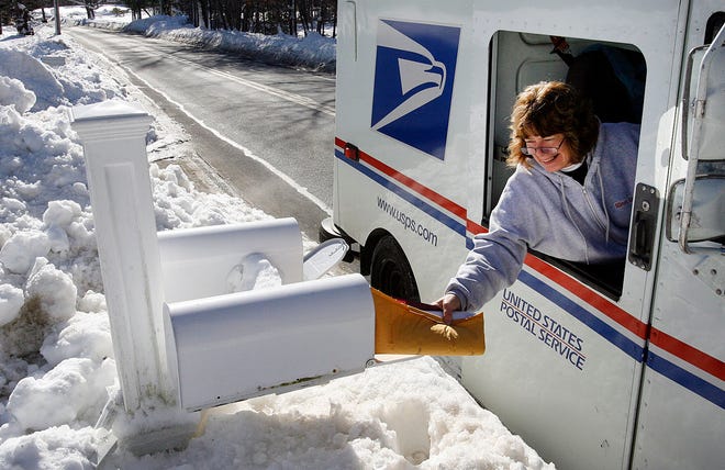 Rural carrier Kathy Holt reaches to get mail in a box on Central Street in Norwell.