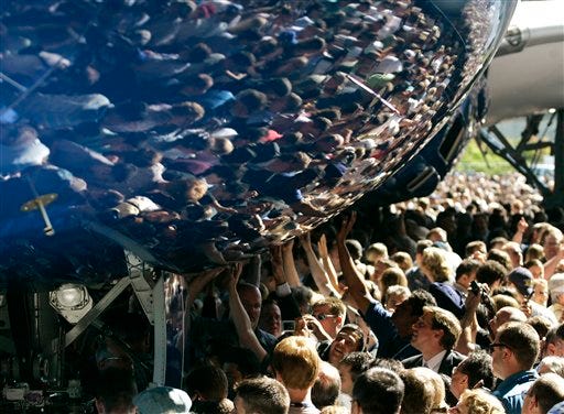Visitors reach out to touch the fuselage of the first production model of the Boeing 787 Dreamliner after it was unveiled to an audience of several thousand at Boeing's assembly plant in Everett, Wash., July 8, 2007.