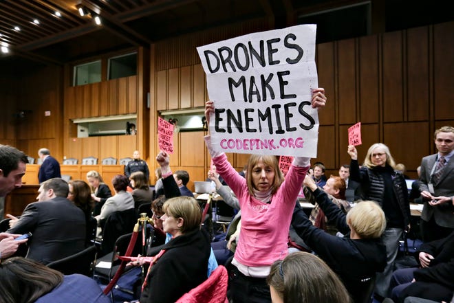 Protesters from CODEPINK, a group opposed to U.S. militarism, including co-founder Medea Benjamin, center, disrupt the start of the Senate Intelligence Committee confirmation hearing for John Brennan, Thursday on Capitol Hill in Washington. (AP Photo/J. Scott Applewhite)