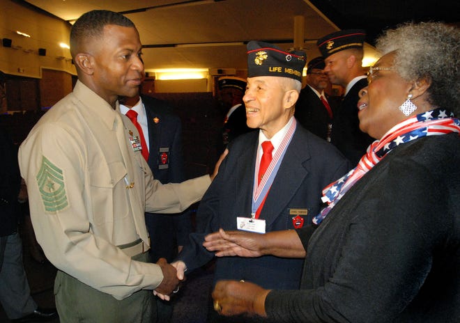Sgt. Maj. Christopher Robinson, 2nd Marine Aircraft Wing sergeant major, left, shakes hands with original Montford Point Marine Master Sgt. Johnnie Thompkins, center, and his wife, Ernell Thompkins at the Cherry Point base theater on Friday. Robinson spoke at a special program honoring the legacy of the Montford Point Marines.