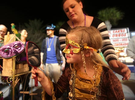 Emma Grace Stokes, 5, checks out her reflection as mom Emily Stokes helps her try on a mask on Friday in Panama City Beach.