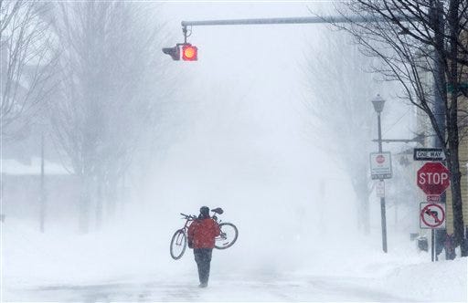 Juan Tavares carries his bike rather than risk riding on a snow-covered street during a blizzard, Saturday, Feb. 9, 2013, in Portland, Maine. The storm dumped more than 30 inches of snow as of Saturday afternoon, breaking the record for the biggest storm on record. (AP Photo/Robert F. Bukaty)