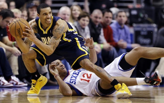 The Sixers' Evan Turner (12) tries to prevent the Pacers' George Hill from controlling the ball during a 2012-13 game.