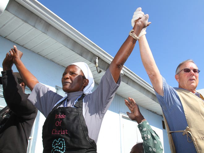 Sister Concepta Najjemba, left, leads the Lord's Prayer as she prays with Dan Cowan, a volunteer, right, before the start of Thanksgiving dinner at Brother's Keeper Soup Kitchen on Northwest Second Street in Ocala, Fla. on Thursday, Nov. 26, 2009.
