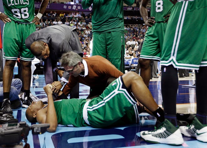 Boston Celtics head coach Doc Rivers, top left, holds the hand of Leandro Barbosa, bottom, as a trainer examines him during the second half of an NBA basketball game against the Charlotte Bobcats in Charlotte, N.C., Monday, Feb. 11, 2013. Barbosa left the game. The Bobcats won 94-91. ()