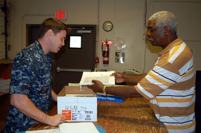 Automated Publishing Specialist Ty Grant (right) of Defense Logistics Agency Document Services helps LSSN Eric Martin of HSM-72 with his printing order.