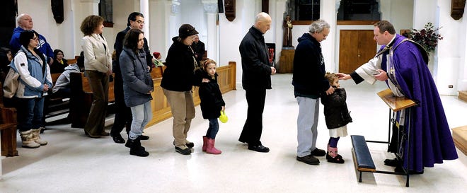 At St. Anne's Shrine, Parish Administrator Rev. Thomas Kocik makes cross with dampened ashes on the forehead of Ava Medeiros, 3, brought forward by her grandfather, Daniel Arruda. Young, old, and all in between lined up for the Ash Wednesday ceremony that marks the beginning of Lent, with Father Kocik announcing beforehand that: "You don't have to be Catholic to receive the ashes; all are welcome."