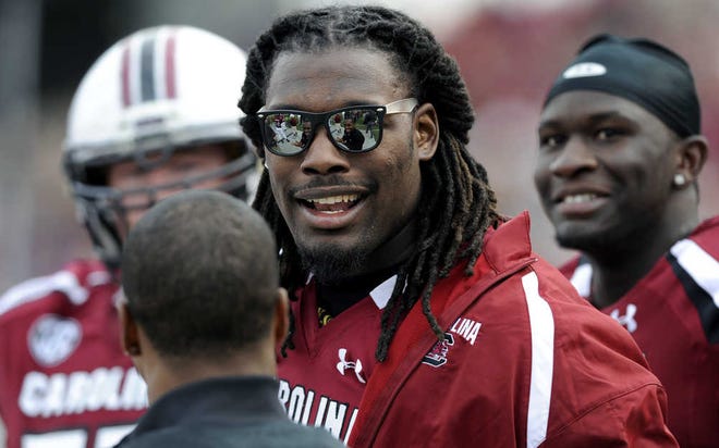 South Carolina defensive end Jadeveon Clowney talks with teammates on the sidelines during a game against Wofford on Nov. 17 in Columbia, S.C. Clowney's status become a trending topic this week, with some columnist suggesting the sophomore might sit out the season to protect his health and likely high draft position in 2014. (Stephen Morton/AP)