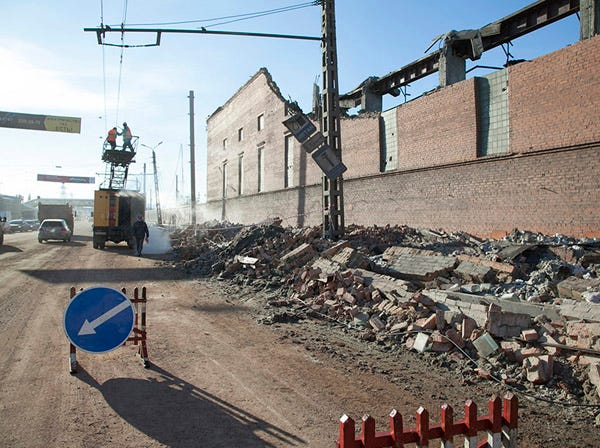 In this photo provided by Chelyabinsk.ru municipal workers repair damaged electric power circuit outside a zinc factory building with about 600 square meters (6000 square feet) of a roof collapsed after a meteorite exploded over in Chelyabinsk region on Friday, Feb. 15, 2013 A meteor streaked across the sky of Russia’s Ural Mountains on Friday morning, causing sharp explosions and reportedly injuring around 100 people, including many hurt by broken glass. (Oleg Kargapolov | Chelyabinsk.ru | Associated Press)