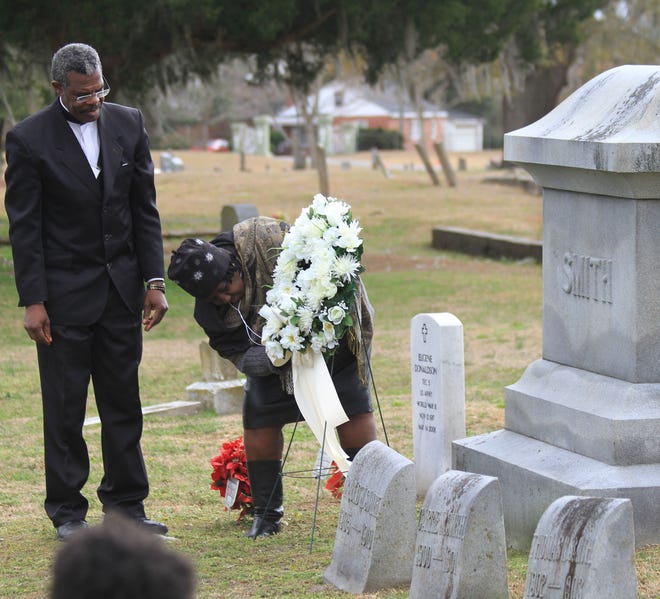 Pastor Robert Johnson and Zelda Bryant, both of the Historic Dryborough Association, lay a wreath at the grave of Isaac H. Smith Jr., a turn-of-the-century leader in New Bern's black community.