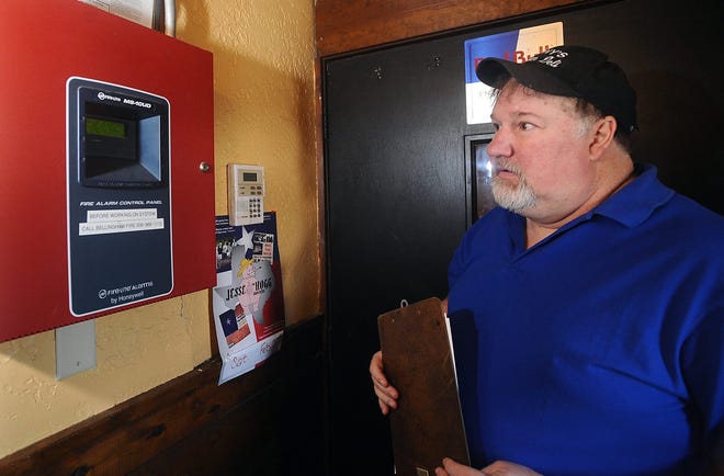 David Lori, owner of the Patriots Bar and Grill in Bellingham, looks at the main panel for the bar's fire alarm system while conducting a fire safety check Friday. Daily News photo by Ken McGagh