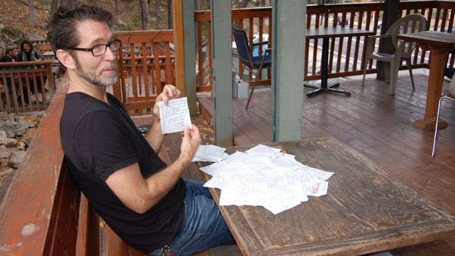 Writer and cab driver Bob Makela, editor of “Barstool Poetry,” seen with dozens of poems used to make the first Austin edition of his book.