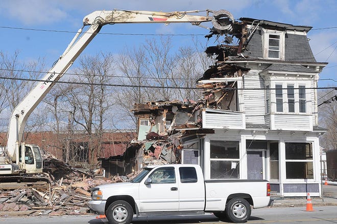 A pickup waits at the traffic light at Court and Washington streets in Taunton as G. Lopes Construction workers tear down the former Mill River Tavern on Wednesday.