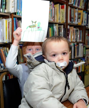 Camryn Ravenelle, 6, stands behind her brother Landon, 2, and holds up a picture she drew while at the Swansea Public Library's Cartoonapalooza on Thursday.