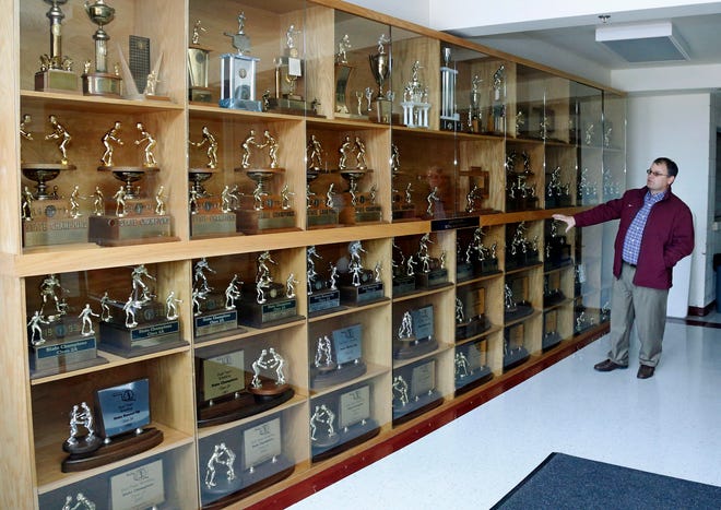 Scott Chenoweth, former Perry High School wrestling coach, looks over the wrestling trophies the school has won in state championships in Perry, Okla. A case had to be specially built to house the trophies. The International Olympic Committee's decision to scrap wrestling has hit hard in Perry. Wrestling is a way of life in the community, and the local high school has racked up more than three-dozen state championships since 1952. (AP Photo/Sue Ogrocki)