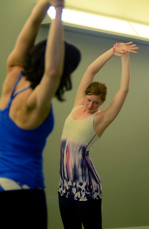 Kara Powers, of Westwood, stretches in Tadasana position during a class Saturday evening at Firefly yoga in Westwood.