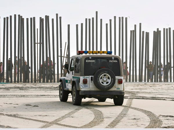 In this Jan. 18, 2009, file photo, a U.S. Border Patrol vehicle sits parked in front of a crowd of people peering through the U.S.-Mexico border fence at Border Field State Park in San Diego. At one time, before the enhanced border fence in the area, the San Diego area held the most popular routes for illegal immigrants heading into the U.S. (AP Photo/Denis Poroy)