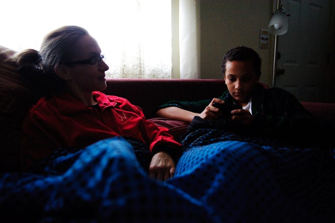 Charlene Morrow and son Malachi Jackson, 13, sit by the light from the living-room window on Tuesday at their home in Hallsville. Their house was one of thousands in Boone County without power as a result of the snowstorm.