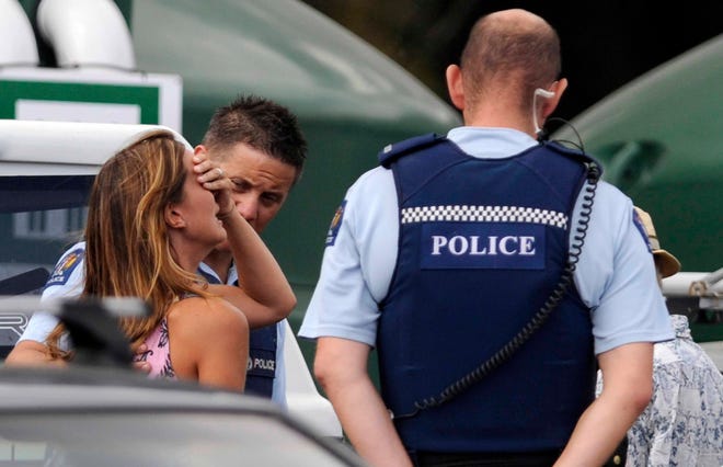 Police comfort a woman believed to be a family member of a man attacked by a shark at Muriwai Beach near Auckland, New Zealand, Wednesday, Feb. 27, 2013. Police said a man was found dead in the water after being "bitten by a large shark." (AP Photo/Ross Land)