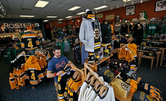 Store manager Anthony Bartoloni sorts through  Bruins merchandise at Roster in Hingham.