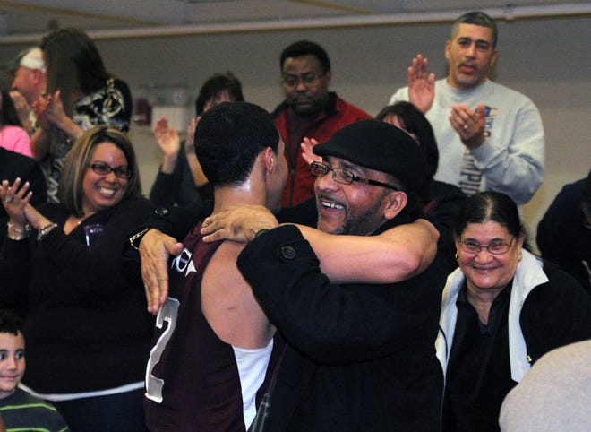 Tony Pires and his father embrace on the sidelines for a joyous hug after the Crusader netted his 1,000th point and the game broke to honor the feat.