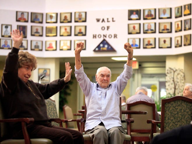 World War II veteran Joseph Kowalski, who is turning 95 on Saturday, a survivor of the North Africa campaign, the invasion of Sicily, D-Day and the Battle of the Bulge, is shown stretching during a group session at his residence, The Atrium, in Gainesville on Thursday.