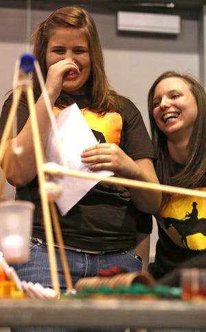 Natalie Jackson, 15, left, and Jessica James, 15, both of West High School in Columbus, laugh as a Ping-Pong ball falls into a plastic cup during a run of their device during the Rube Goldberg Machine Contest.