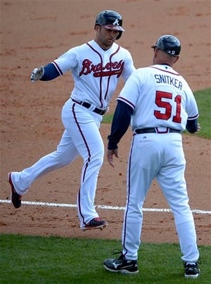 Atlanta Braves' Dan Uggla, left, is congratulated by coach Brian Snitker (51), while rounding third base, after hitting a solo home run during the sixth inning of an exhibition spring training baseball game against the Detroit Tigers in Kissimmee, Fla., Sunday, March 3, 2013. The Braves won 6-1.(AP Photo/Phelan M. Ebenhack)