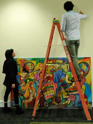 Ted Kuhn, right, and Didi Dunphy, curator for the Classic Center, hang paintings in the Classic Center in Athens, Ga., Thursday, Feb. 7, 2013. (AJ Reynolds/Staff)