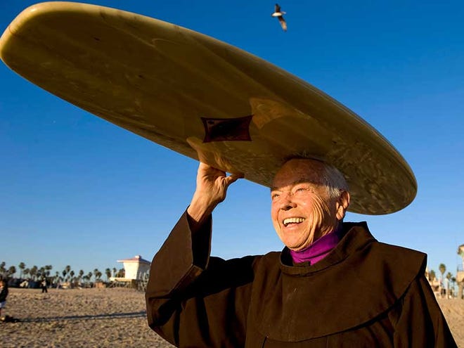 Father Christian Mondor, a Franciscan brother at Sts. Simon & Jude Parish in Huntington Beach, California, carries his surfboard near the Huntington Beach pier. Father Christian learned to surf at age 70, and spearheads the annual Blessing of the Waves each October.
