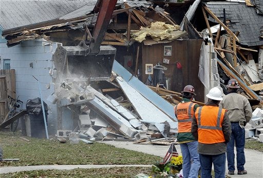 Demolition experts watch as the home of Jeff Bush, 37, is destroyed Sunday in Seffner, Fla. The 20-foot-wide opening of the sinkhole was almost covered by the house, and rescuers said there were no signs of life since the hole opened Thursday night.