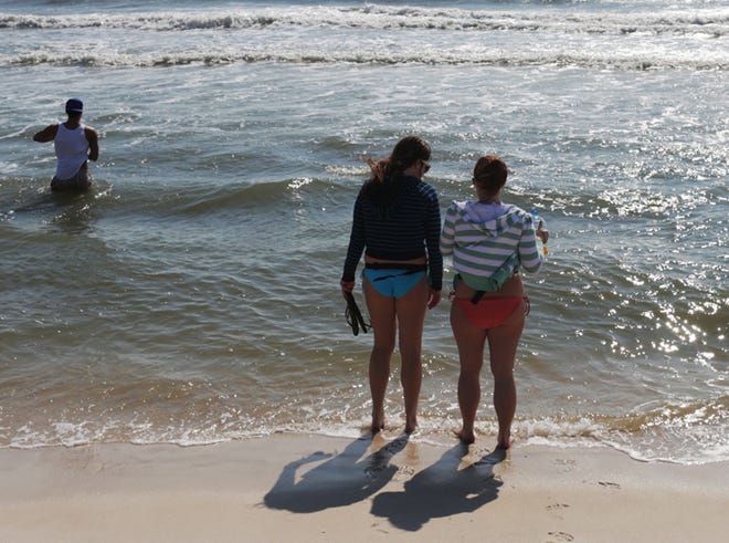 April Swords, left, and Amanda Hopkins, right, stand at the edge of the gulf on a cold afternoon during a party on the beach at Spinnaker Beach Club in Panama City Beach, Fla. on Sunday, March 3, 2013.