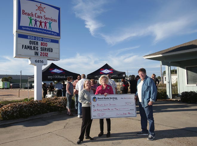 Felicia Cook, 2013 Beach Care Services president, from left, holds a check presented to the nonprofit organization from Barbara Fraley-Morris, CEO of Beach Waste Services, and Jack Morris, CFO of Beach Waste Services, during a grand opening ceremony at the nonprofit’s new location Monday in Panama City Beach.