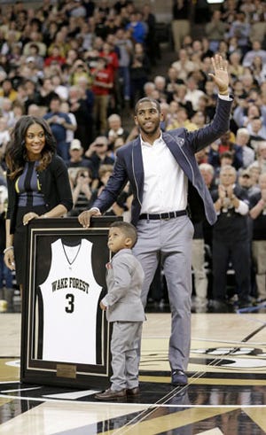 Former Wake Forest star Chris Paul waves to the crowd during halftime of Saturday's game while accompanied by his wife, Jada Paul, and his son, Christopher Emmanuel Paul II.