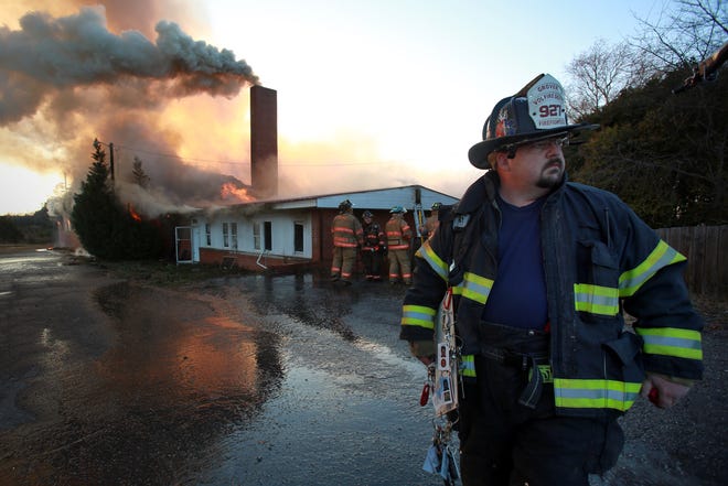 Grover Fire Department fireman, Steven Richardson, looks away as the old Minette Mills building in Grover burns in the background Thursday evening. (Ben Earp/The Star)