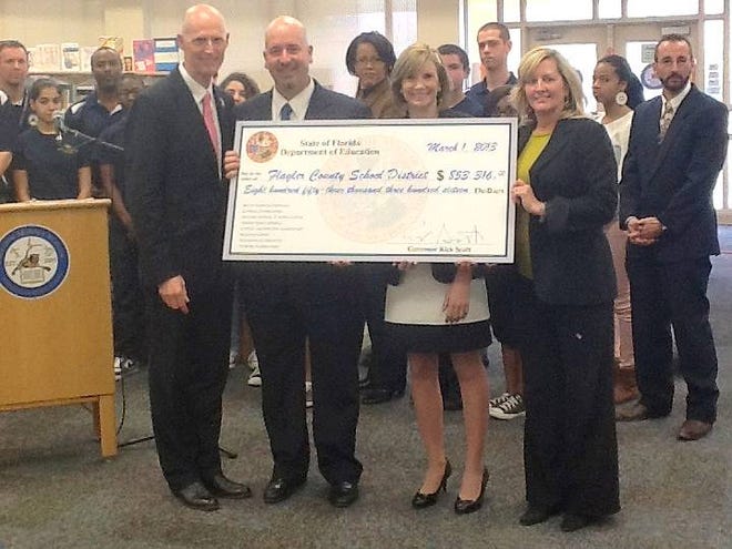 Flagler County school officials receive a symbolic check for $853,316 from Gov. Rick Scott. Pictured with the governor, from left, are Jacob Oliva, assistant superintendent; Colleen Newman, district teacher of the year; and Sabrina Crosby, district communications coordinator.