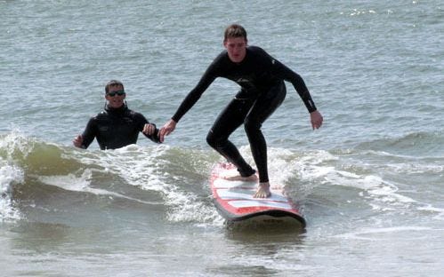 Marcel, a tourist from Germany, learning to surf at St. Andrews State Park as part of a Mr. Surf's Surf Shop class.