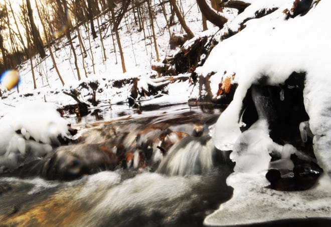 A small brook splashes through rocks and ice Wednesday at Sanctuary Woods Preserve.
