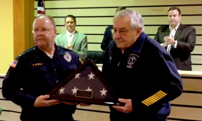 Lumberton Police Lt. Edward Begolly presents an American Flag to retired Office of Emergency Management coordinator Bill Warren on Tuesday at the township committee meeting. Warren served as the township?s OEM coordinator since 1998. The flag was flown over the Lumberton Municipal Building during Superstorm Sandy.