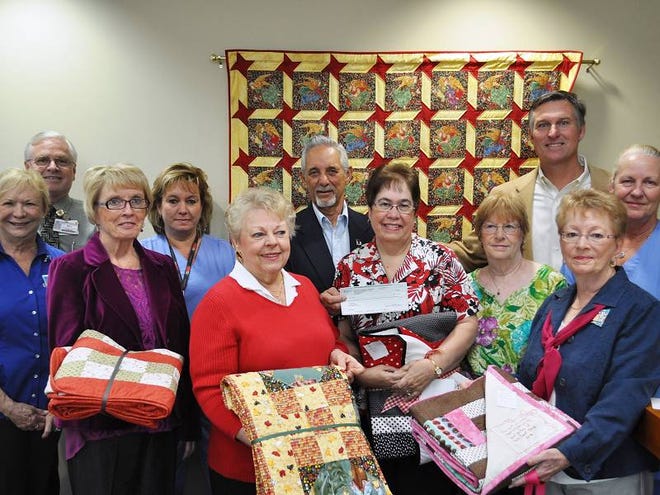 Members of the Florida Hospital Flagler Foundation present a check for $1,000 to a group of women who make quilts for patients at the Stuart F. Meyer Hospice House. Pictured, front row from left are Judy Schlink; Lori Parker; Pam Taylor; Lea Rich; back row, from left, Susan Cole; Bill Tol, Florida Hospital Flagler Foundation development officer; Sally Wilson; Tony Papandrea, Florida Hospital Flagler Foundation board member; Donna Levine; and John Subers, Florida Hospital Flagler Foundation administration director.