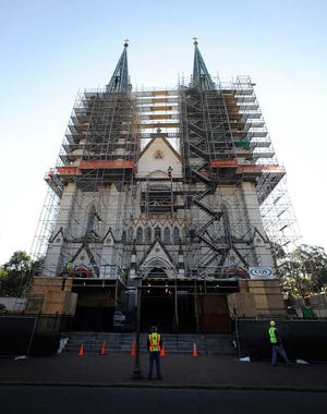 In this Thursday, March 14, 2013 photo, workers stand in front of the Cathedral of St. John the Baptist during major repairs on the church's Gothic architecture, in Savannah, Ga. Deep cracks were discovered between the bricks that form the towering twin steeples and is expected to cost the Roman Catholic Diocese of Savannah about $1.5 million to fix. (AP Photo/Stephen Morton)
