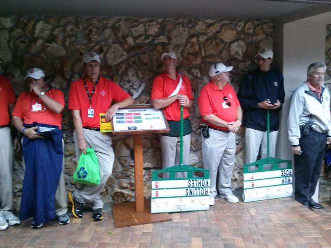 Volunteers and standard bearers huddle in a breezeway near the Bay Hill Club and Lodge clubhouse on Sunday during a thunderstorm that interrupted the Arnold Palmer Invitational.