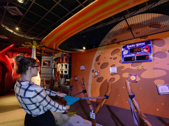 This March 22, 2013 photo shows guests taking their best shot in a competition with fellow players using mini-Angry Birds launched in a slingshot to zap space pigs at the Kennedy Space Center Visitor Complex in Cape Canaveral. (AP Photo/Delaware North, Joe Cascio)