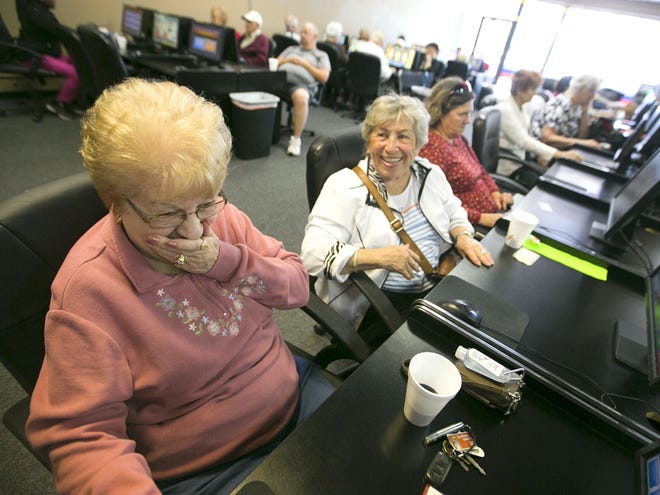Jean Bauder, left, and her friend Evelyn Weinreb share a moment while enjoying the games at Palms Internet Cafe in Ocala on Monday.