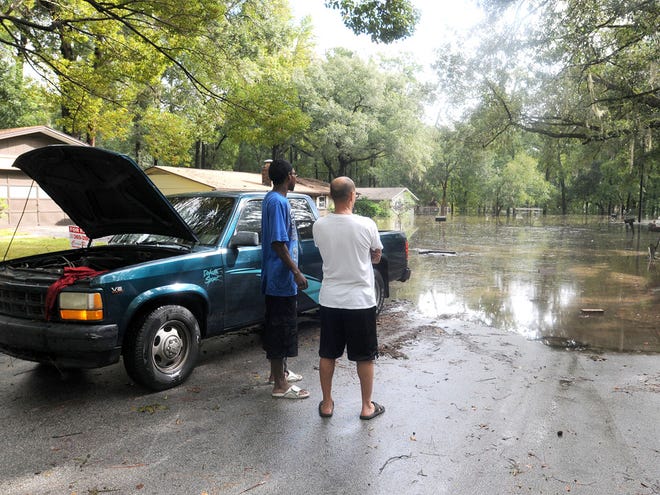 In this Oct. 10, 2011 file photo, Herman Benjamin, left, and Edwin Hernandez stand by a stranded car next to the flooded Northeast Fourth Street in Ocala. The city has targeted the area for improvements to stormwater drainage systems that coulde alleviate flooding problems.