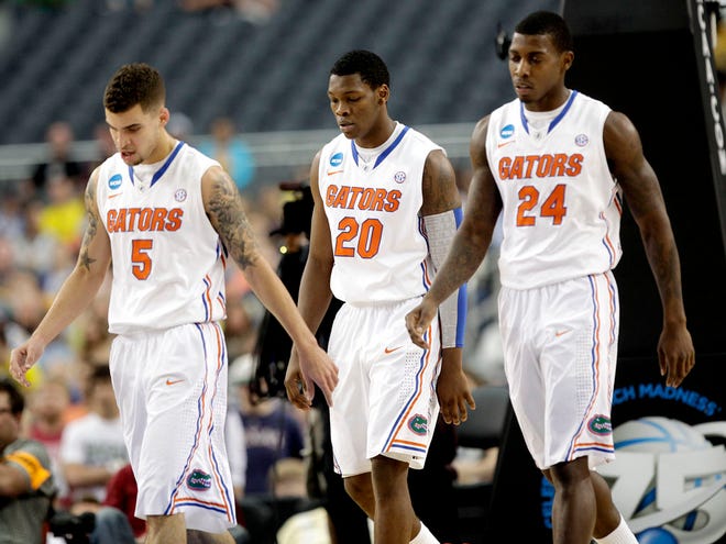 Florida Gators guard Scottie Wilbekin, guard Michael Frazier II and forward Casey Prather walk off the court after calling a time out against the Michigan Wolverines during the first half of the Elite Eight on Sunday at Cowboys Stadium in Arlington, Texas.